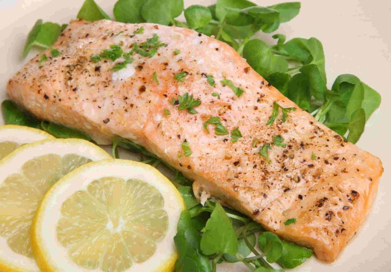 Filet de saumon mariné et ensuite cuit au four servi avec laitue et tranches de citron