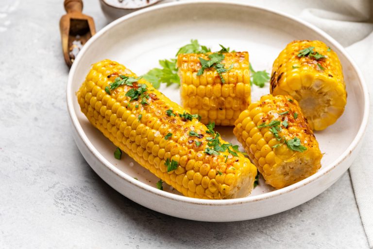 Épis de maîs à la friteuse à air avec beurre, sel et persil.