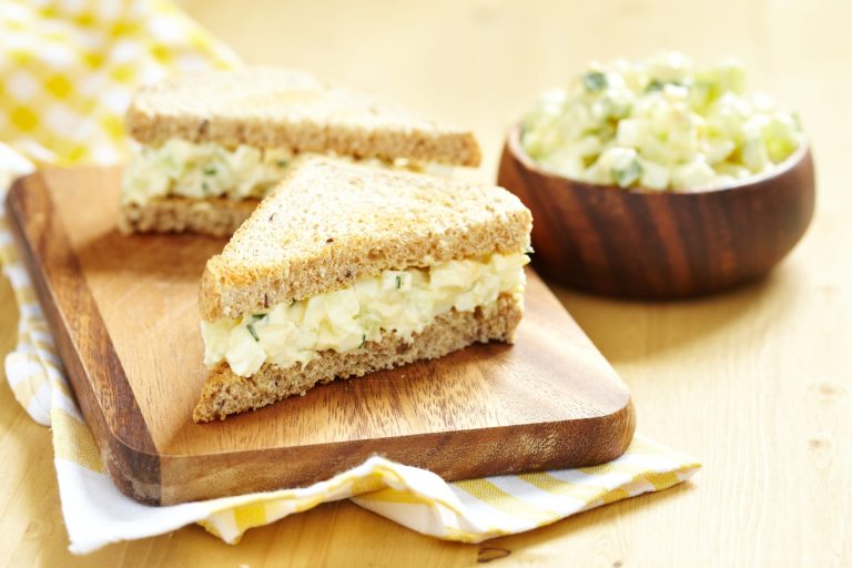 Sandwichs aux oeufs avec bol de garniture de salade aux oeufs servis sur une planche de bois