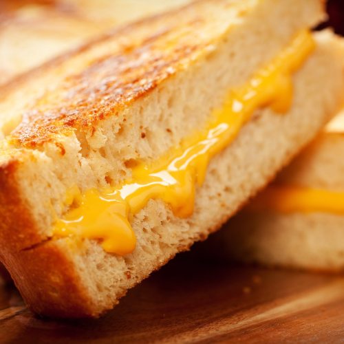 Grilled cheese à la friteuse à air avec fromage jaune et pain blanc sur une planche de bois