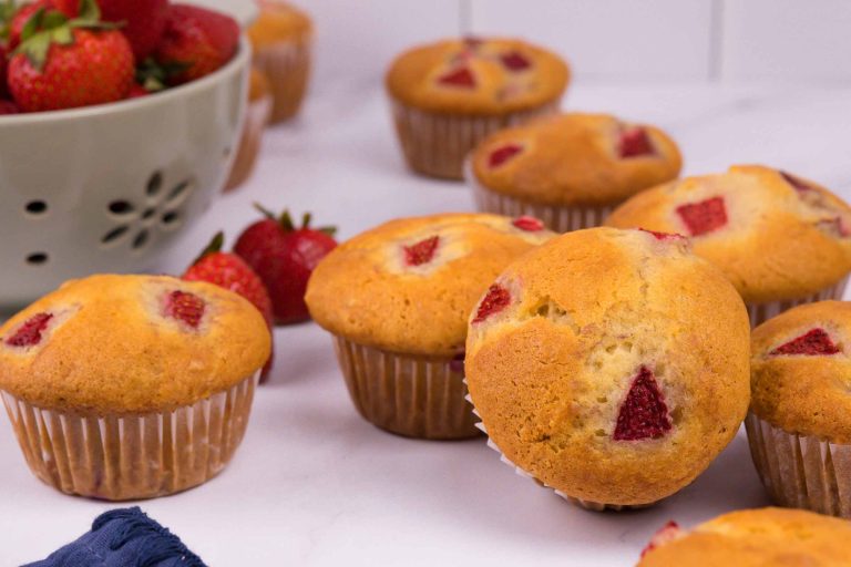 Plusieurs muffins aux fraises sur fond blanc avec quelques fraises en décoration