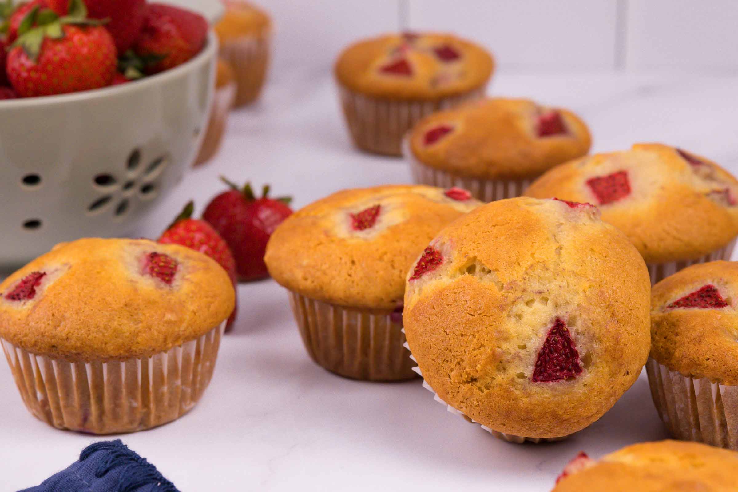 Plusieurs muffins aux fraises sur fond blanc avec quelques fraises en décoration