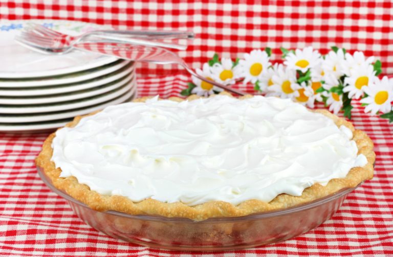 Tarte à la noix de coco maison couverte de crème fouettée.
