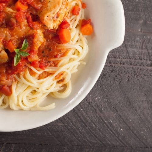 Poulet cacciatore cuit à l'autocuiseur Instant Pot servi sur des spaghettis dans un bol blanc