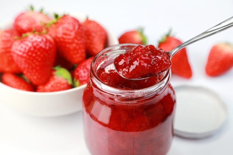 Pot de confiture de fraises maison avec des bols remplis de fraises fraîches