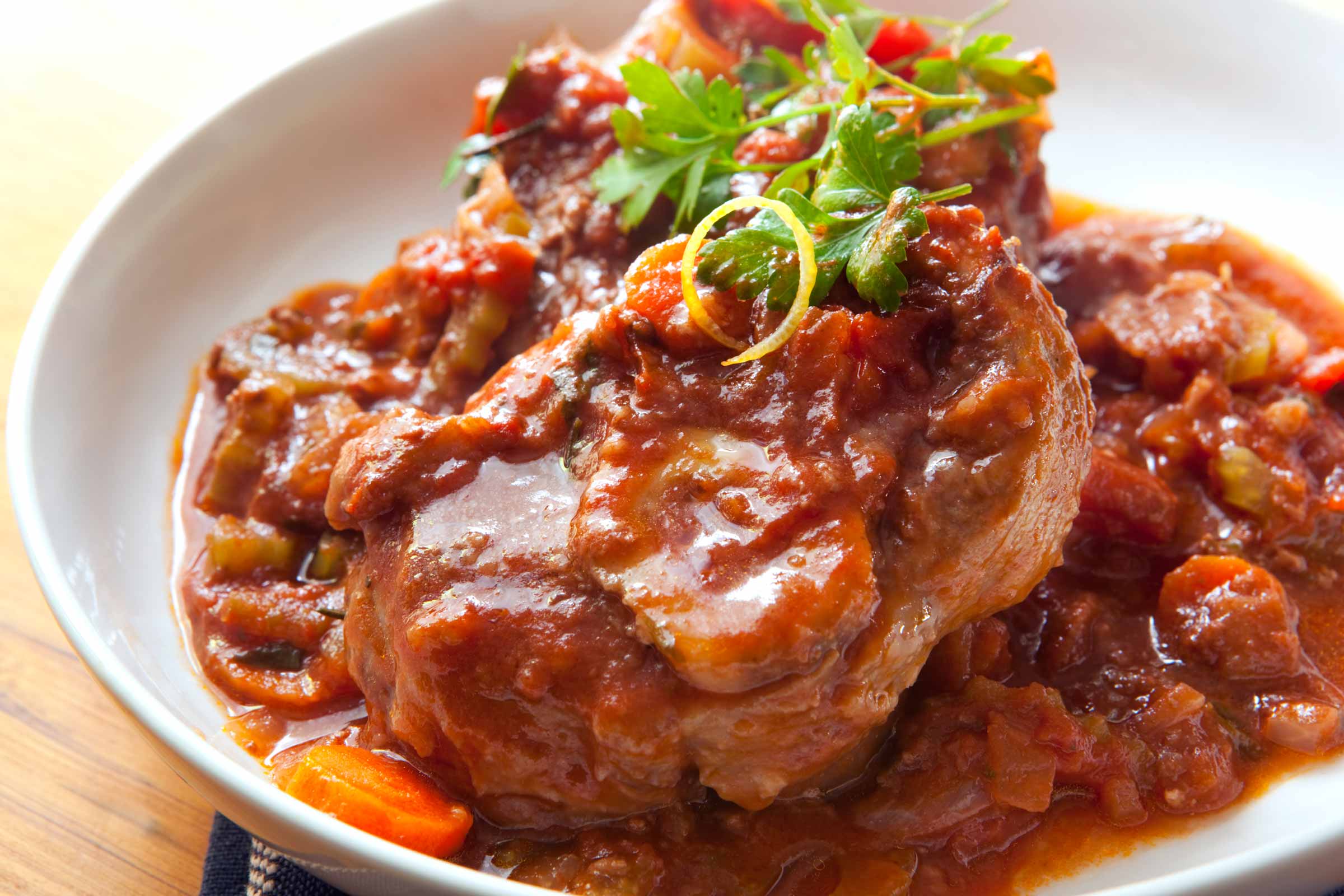 Osso buco à l'italienne de veau en sauce tomate servi sur une assiette blanche
