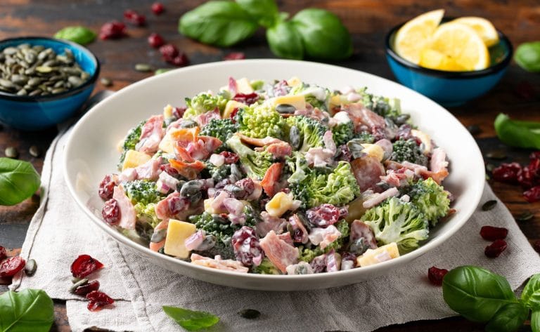 Salade de brocoli et bacon avec fromage et canneberges séchées servie dans un bol blanc