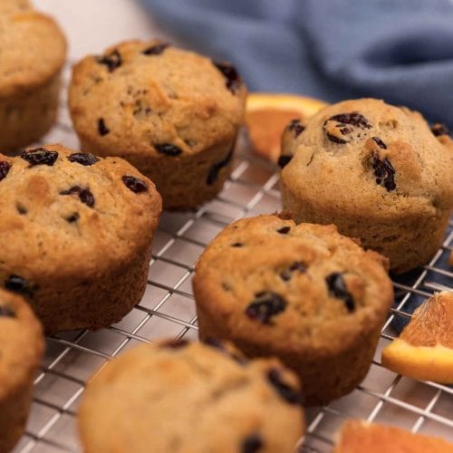 Muffins aux canneberges et à l'orange sur une grille avec des morceaux d'orange