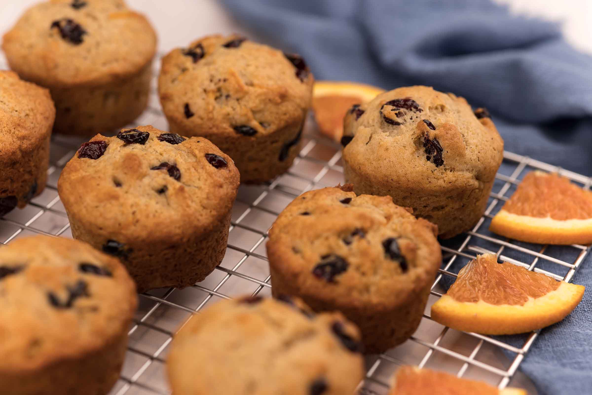 Muffins aux canneberges et à l'orange sur une grille avec des morceaux d'orange