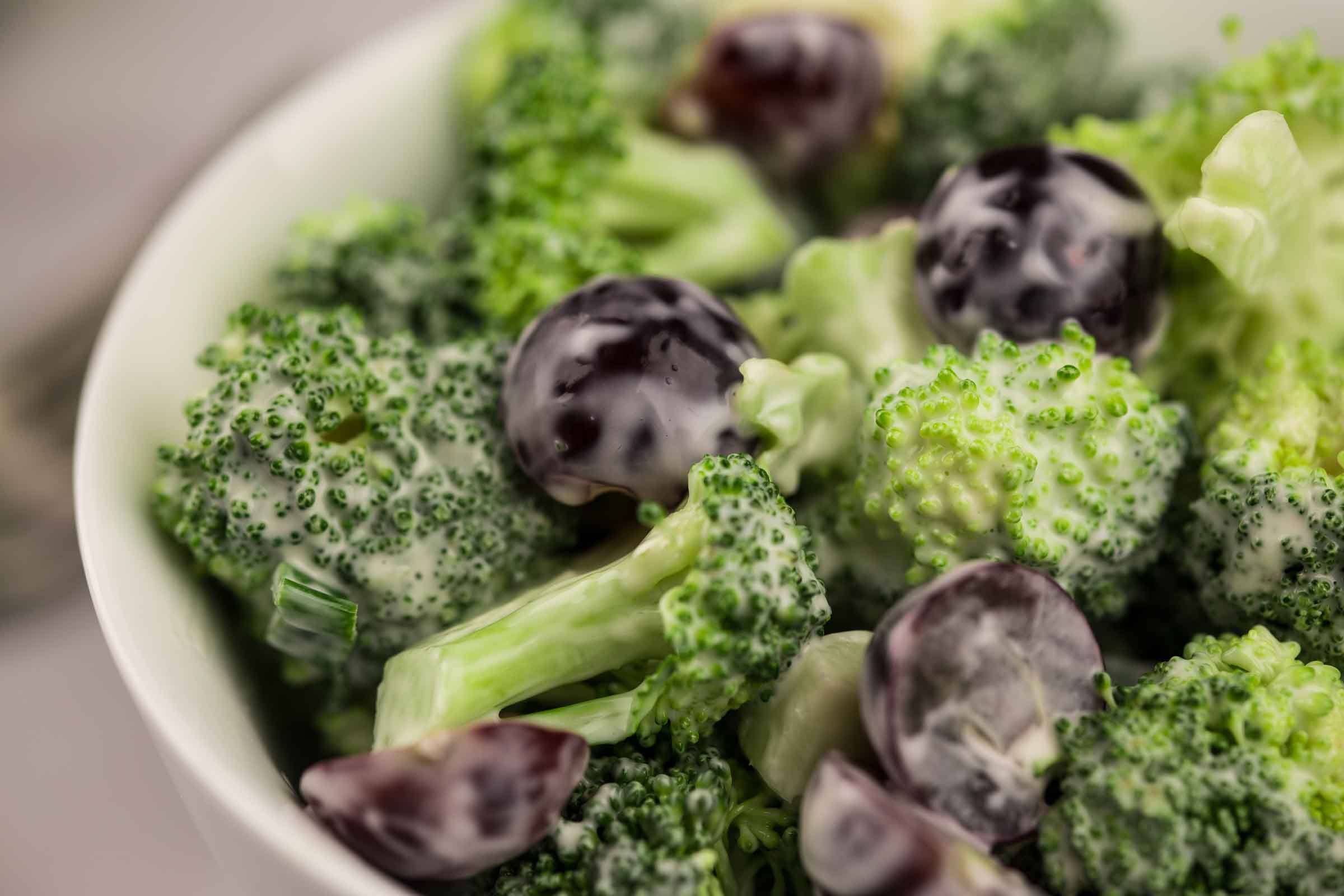 Salade avec bouquets de brocoli et des morceaux de raisins frais avec vinaigrette crémeuse servie dans un bol blanc