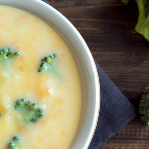 Soupe crémeuse au brocoli, chou-fleur et carottes servie dans un bol blanc sur une table de bois
