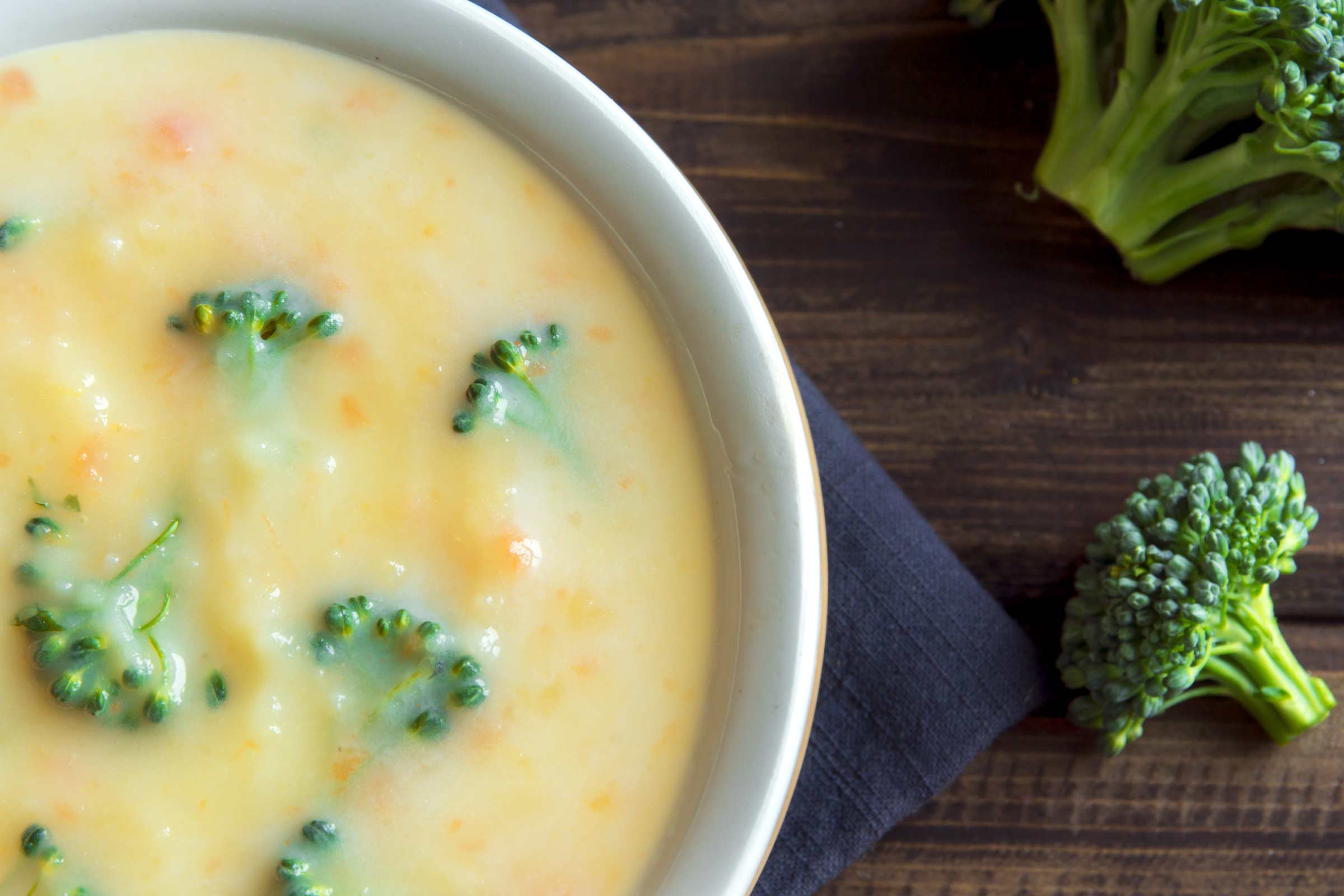 Soupe crémeuse au brocoli, chou-fleur et carottes servie dans un bol blanc sur une table de bois