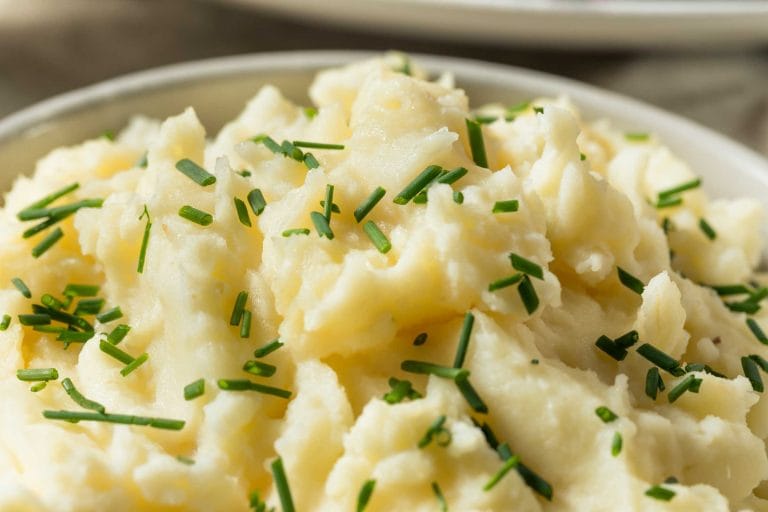 Purée de pommes de terre dans un bol blanc garni de ciboulette hachée