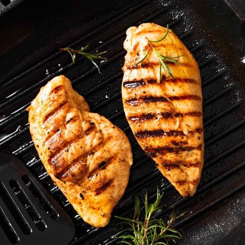 Une marinade grecque aromatise ces poitrines de poulet qui grillent sur le barbecue.