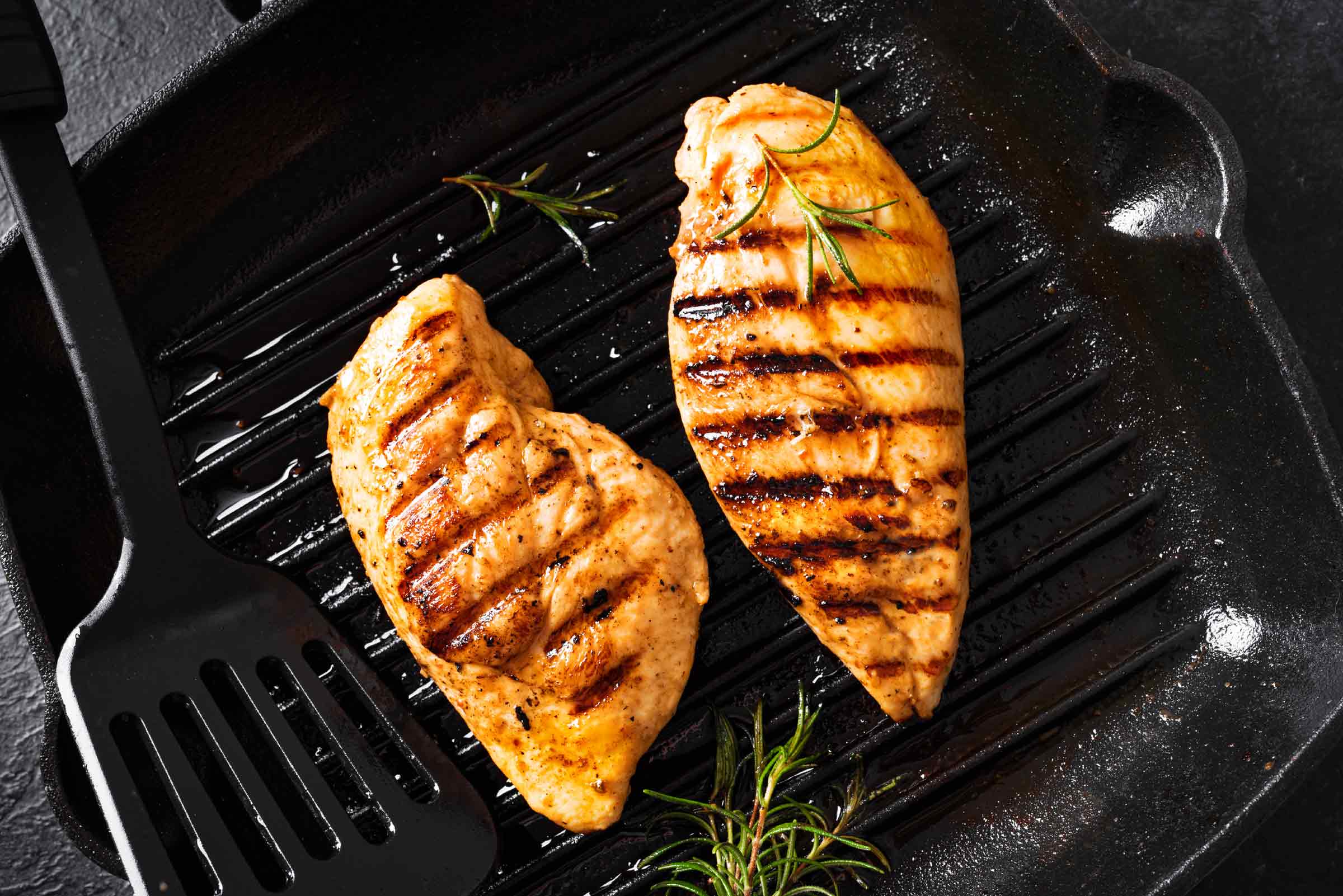 Une marinade grecque aromatise ces poitrines de poulet qui grillent sur le barbecue.